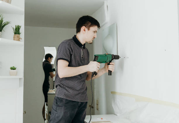 a young man drills a hole in the wall. - lifehack foto e immagini stock