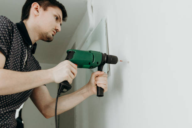 a young man drills a hole in the wall. - lifehack foto e immagini stock