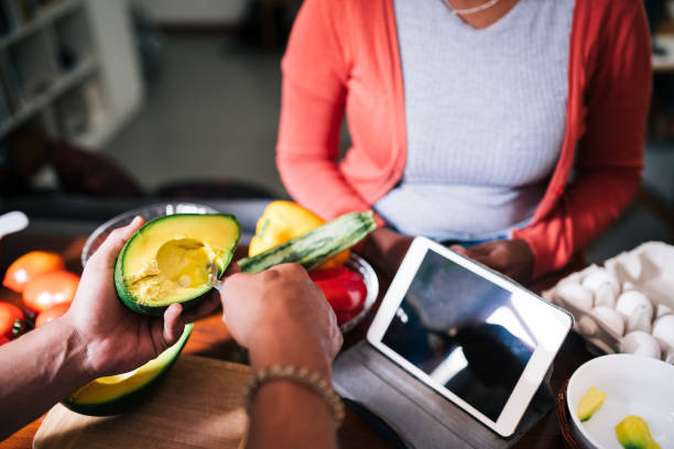 coppia che prepara un pasto insieme da una ricetta online su un tablet - lifehack foto e immagini stock