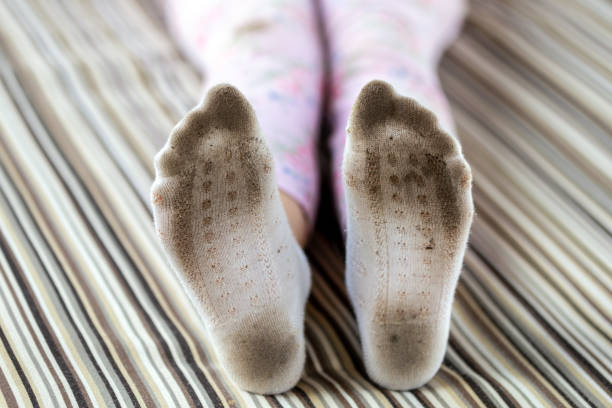 coppia di piedini per bambini con calzini bianchi macchiati sporchi. calze sporco bambino mentre si gioca all'aperto. concetto di problemi di sbiancamento e lavaggio dei vestiti per bambini - lifehack foto e immagini stock