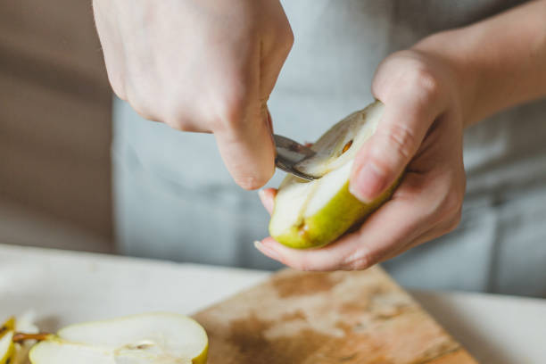 eestracting il nucleo di una pera o di una mela con un cucchiaino - lifehack da cucina - lifehack foto e immagini stock