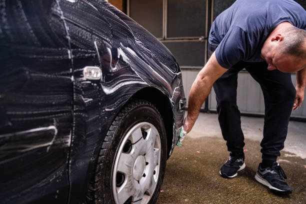 uomo adulto medio che lava l'auto nel suo cortile - lifehack foto e immagini stock